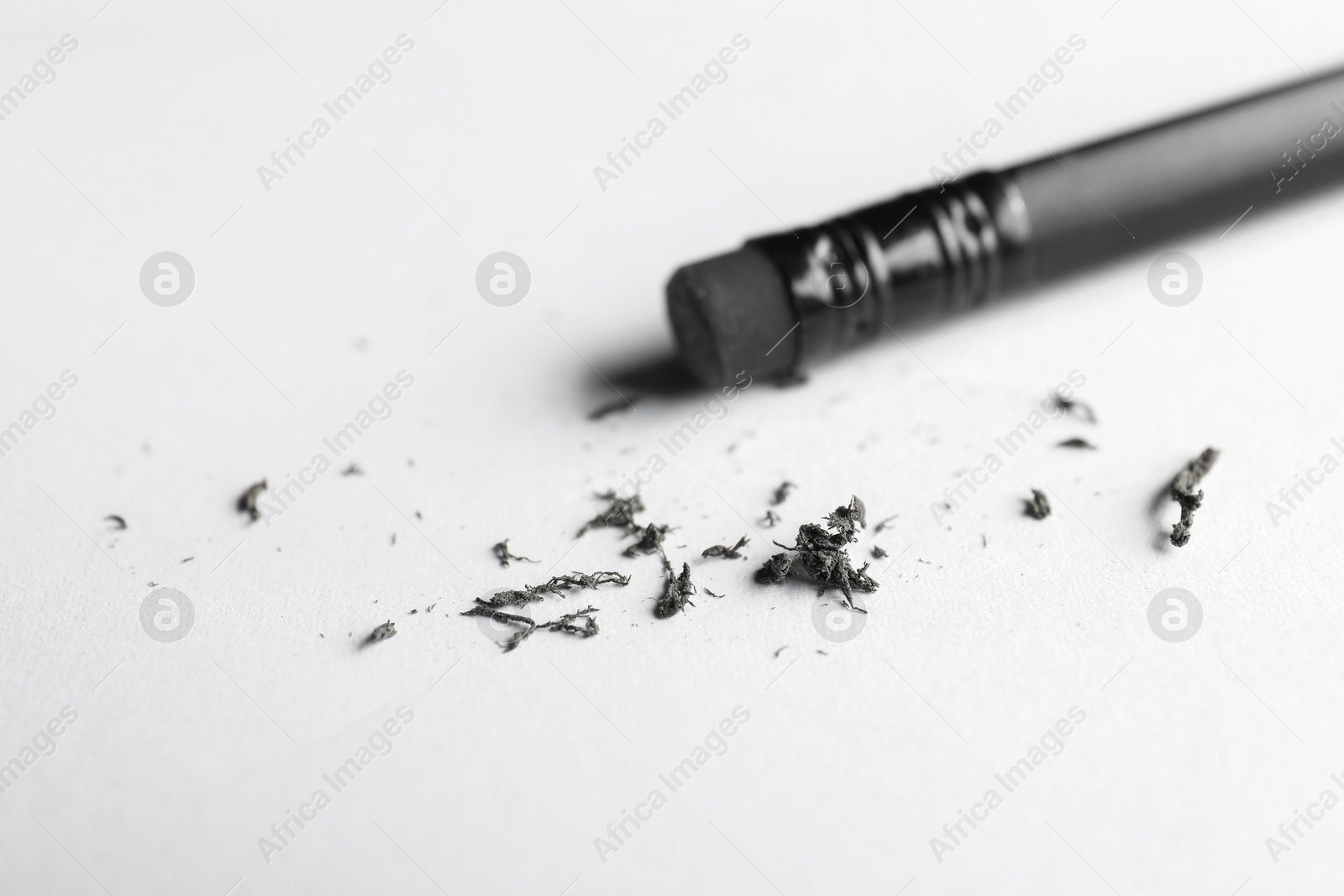 Pencil with eraser and scraps on white sheet of paper, closeup Photo of Pencil with eraser and scraps on white sheet of paper, closeup