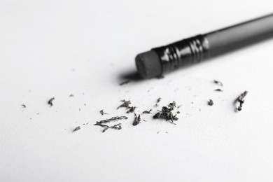 Photo of Pencil with eraser and scraps on white sheet of paper, closeup