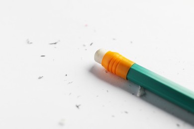 Photo of Pencil with eraser and scraps on white sheet of paper, closeup