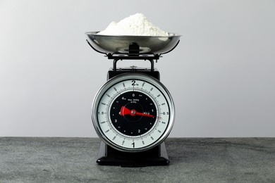 Photo of Retro mechanical kitchen scale with flour on grey table