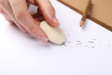 Photo of Woman rubbing eraser against paper at brown table, closeup