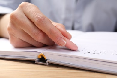 Photo of Woman rubbing eraser against paper at wooden table, closeup