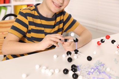 Boy making DNA structure model at desk indoors, closeup