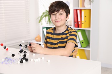 Boy making DNA structure model at desk indoors