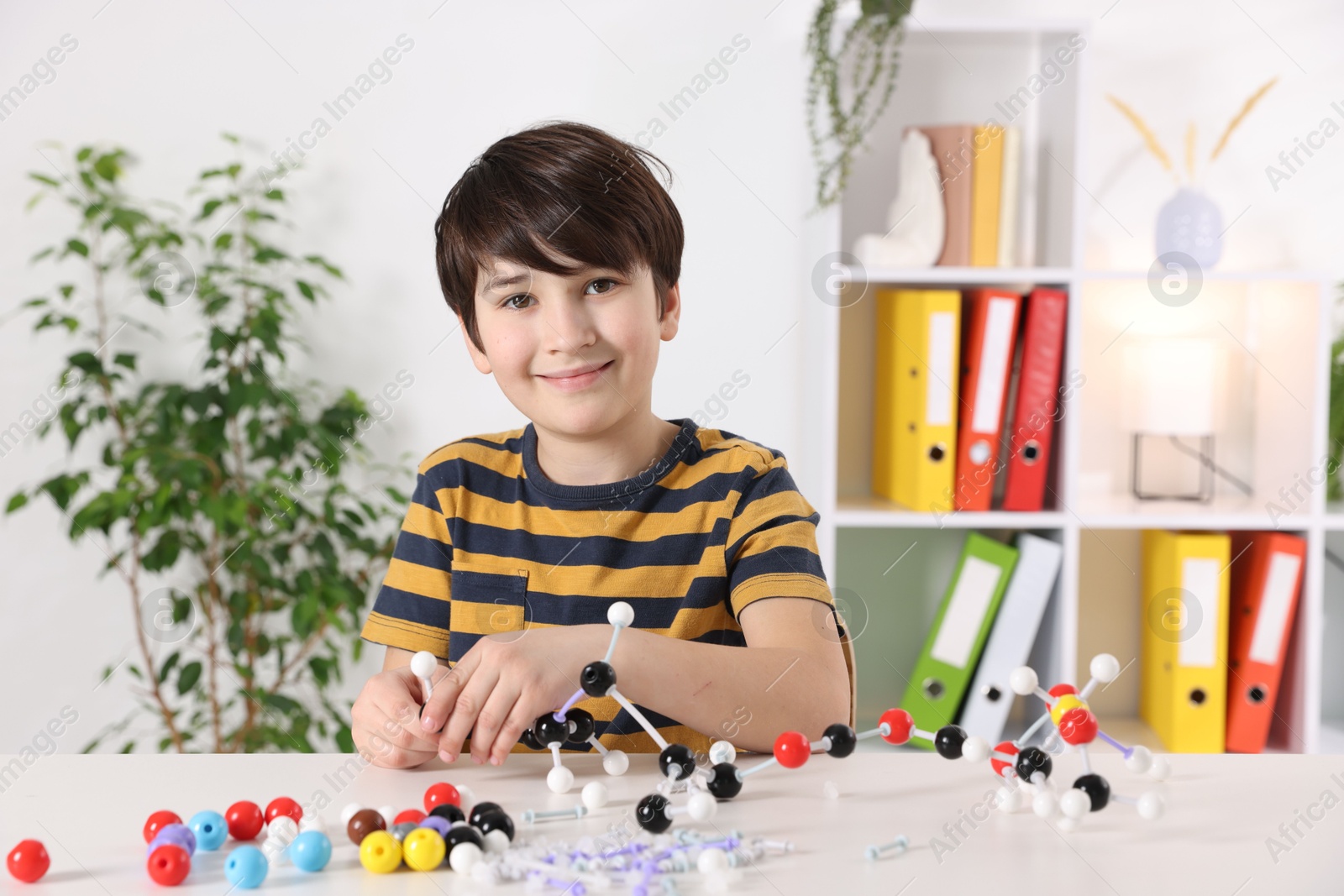 Photo of Boy making DNA structure model at desk indoors