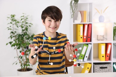 Boy with DNA structure model at desk indoors