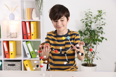 Boy with DNA structure model at desk indoors