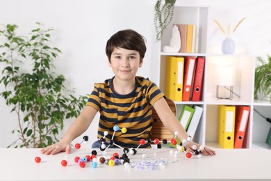 Boy with DNA structure model at desk indoors