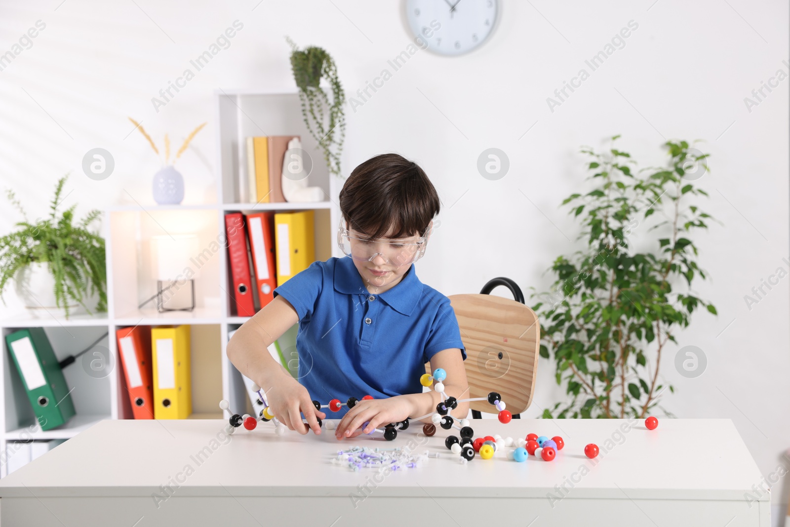 Photo of Boy making DNA structure model at desk indoors