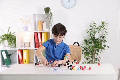 Photo of Boy making DNA structure model at desk indoors