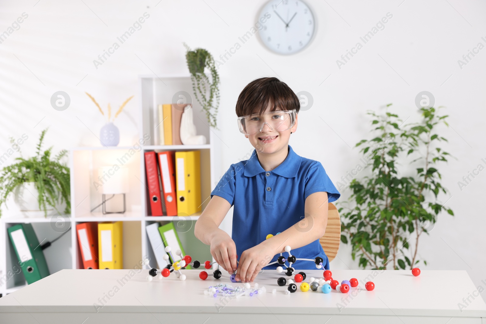 Photo of Boy making DNA structure model at desk indoors. Space for text