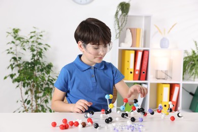 Photo of Boy making DNA structure model at desk indoors