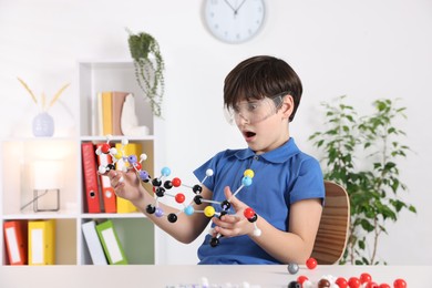 Photo of Emotional boy with DNA structure model at desk indoors