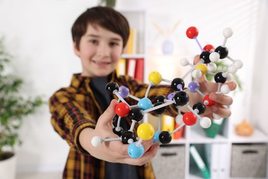 Boy with DNA structure model indoors, selective focus