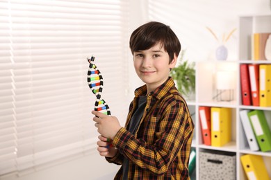 Smiling boy with DNA structure model indoors