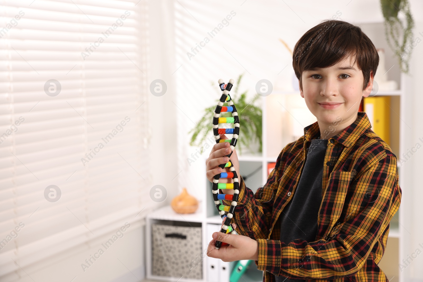 Photo of Smiling boy with DNA structure model indoors. Space for text