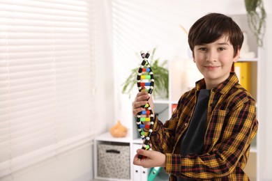 Photo of Smiling boy with DNA structure model indoors. Space for text