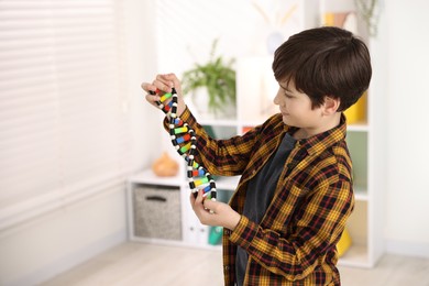 Boy with DNA structure model indoors. Space for text