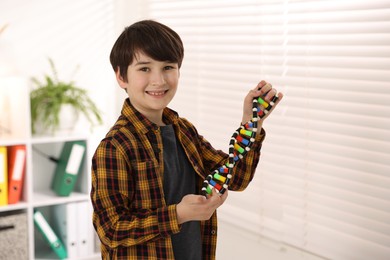 Smiling boy with DNA structure model indoors