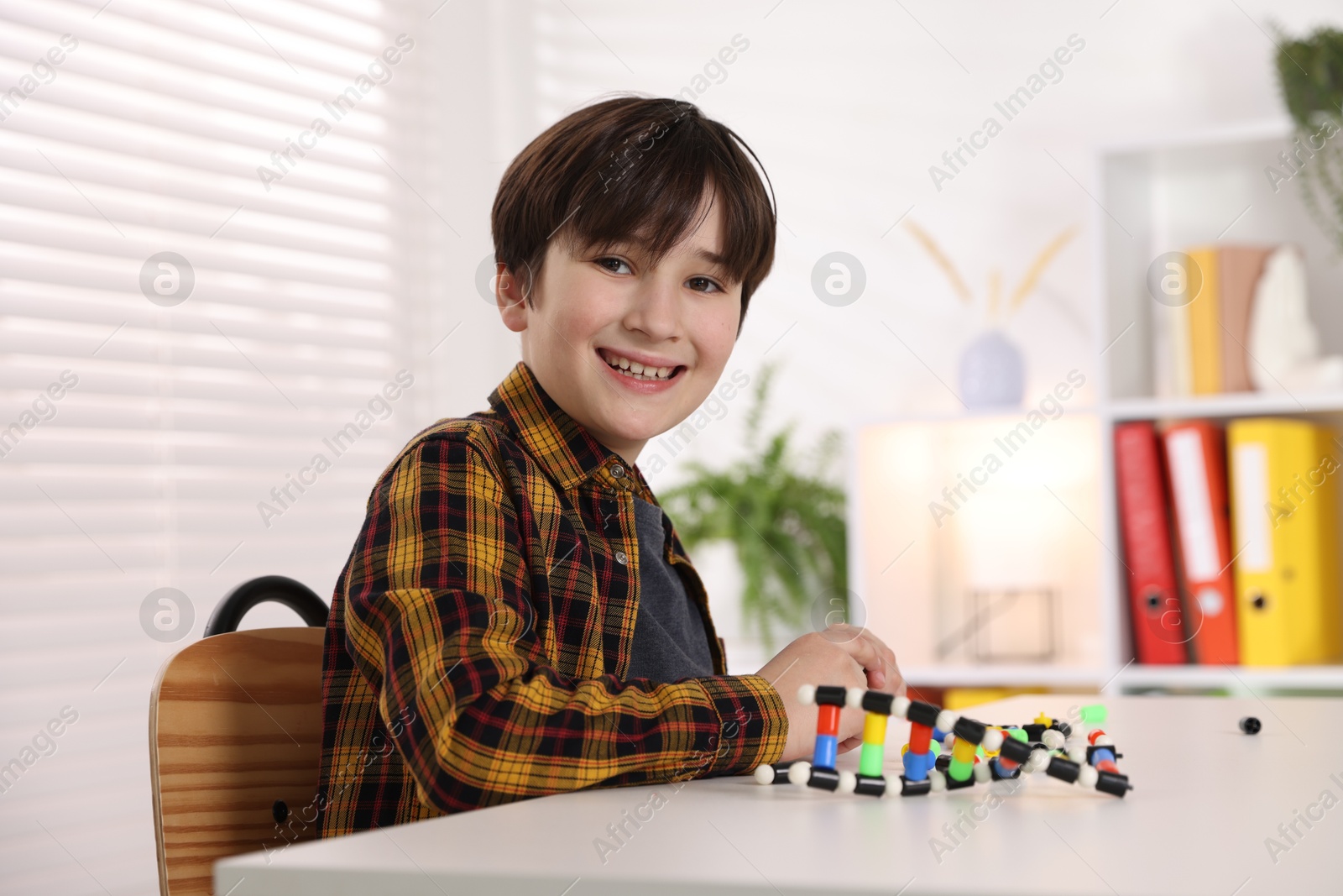 Photo of Boy making DNA structure model at desk indoors