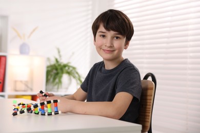 Boy making DNA structure model at desk indoors