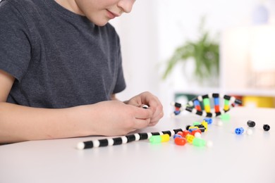 Boy making DNA structure model at desk indoors, closeup