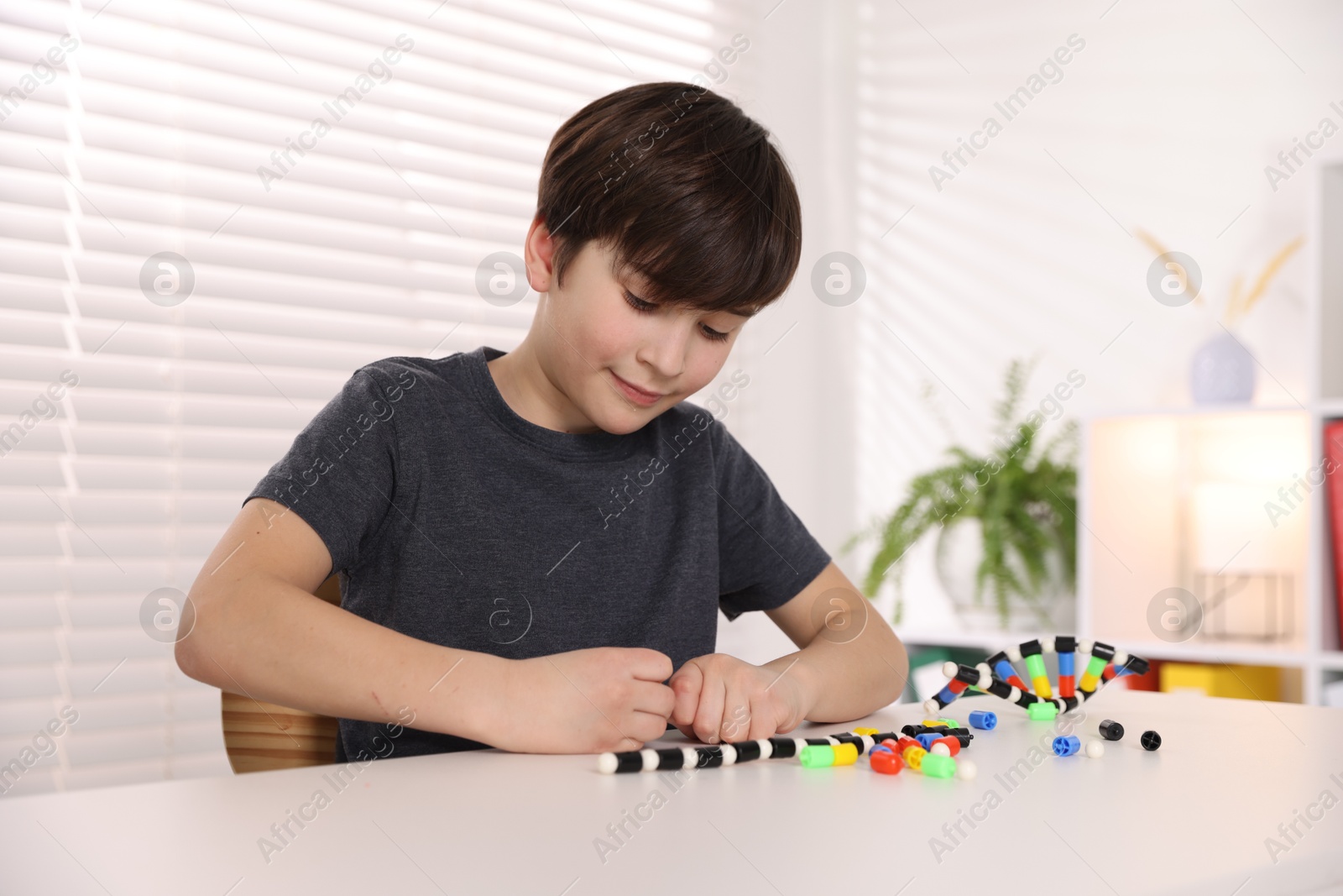 Photo of Boy making DNA structure model at desk indoors