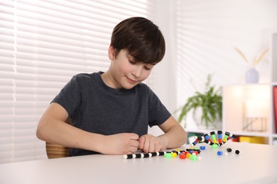 Boy making DNA structure model at desk indoors