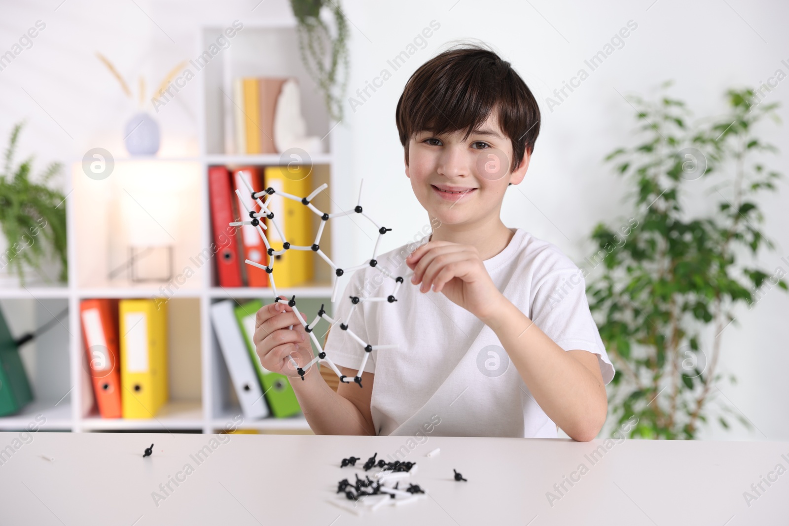 Photo of Boy making DNA structure model at desk indoors