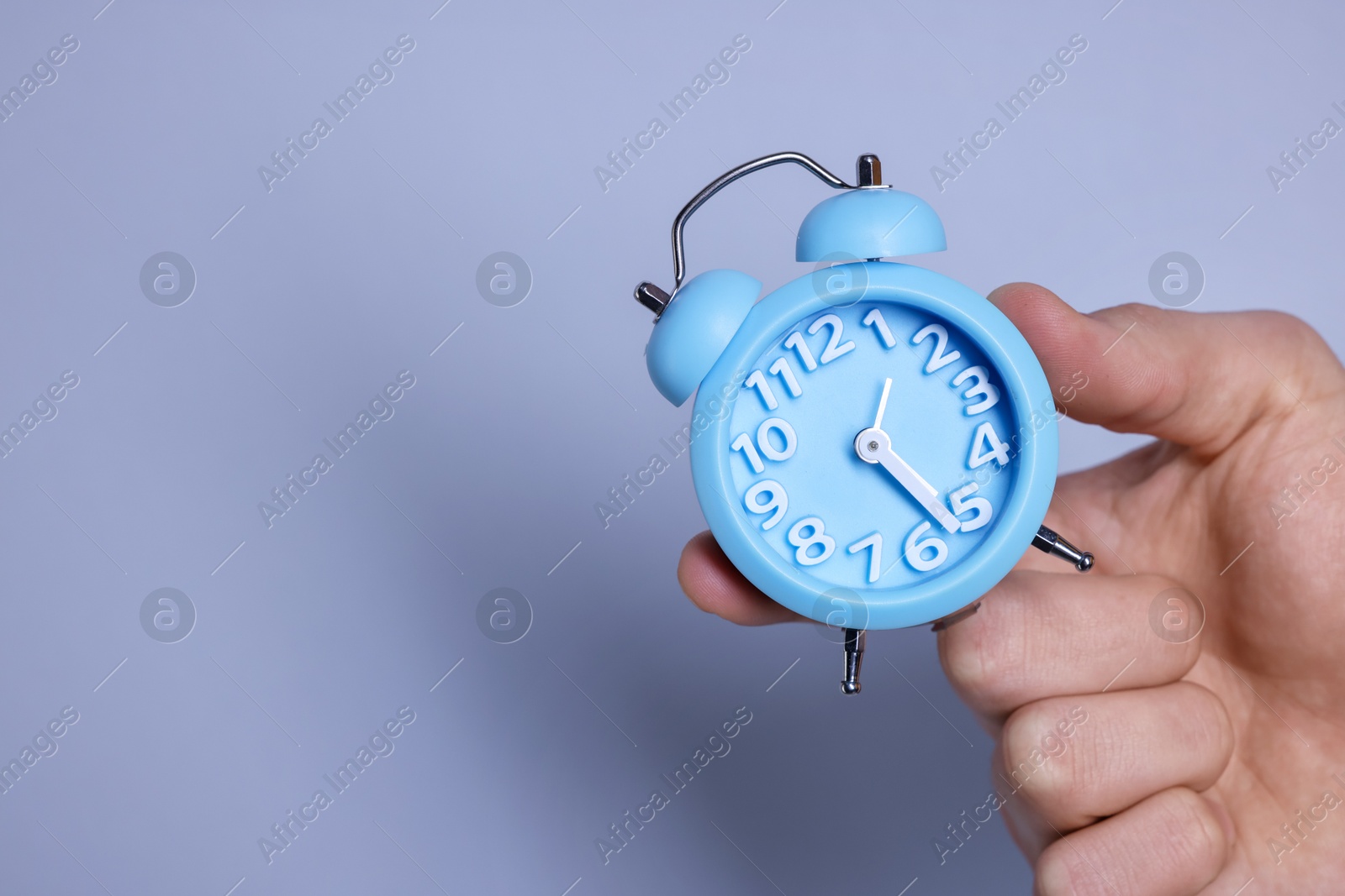 Photo of Man with light blue alarm clock on grey background, closeup. Space for text