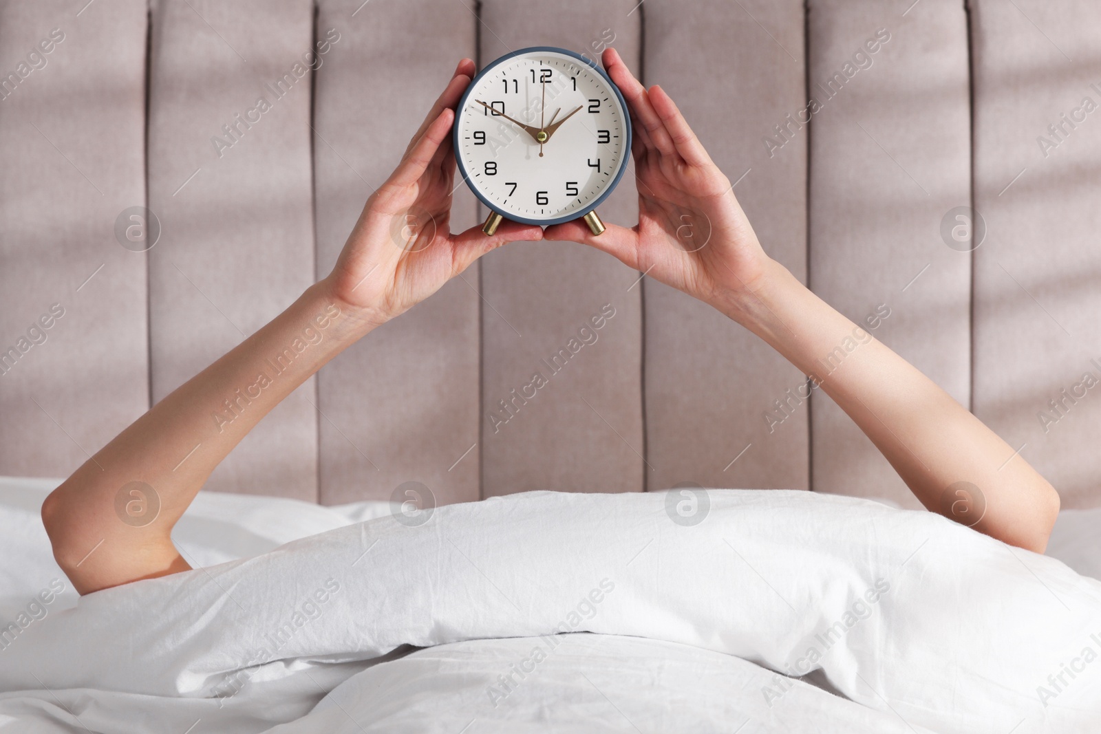 Photo of Woman with alarm clock in bed at home, closeup. Good morning