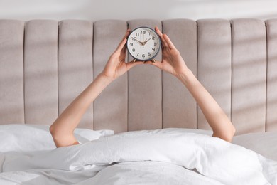 Photo of Woman with alarm clock in bed at home, closeup. Good morning