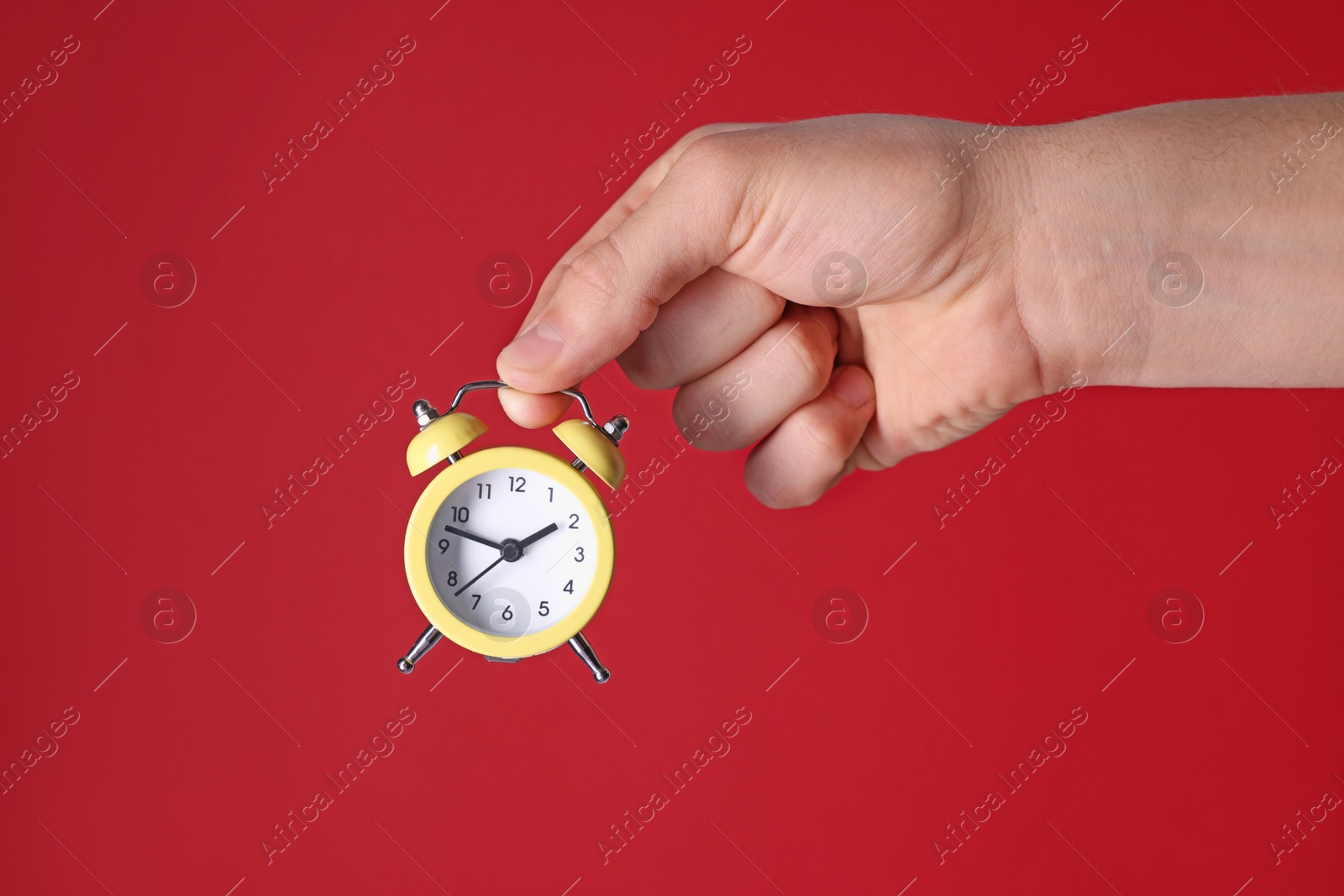 Photo of Man with alarm clock on red background, closeup