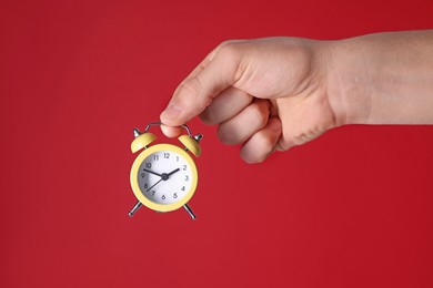 Man with alarm clock on red background, closeup