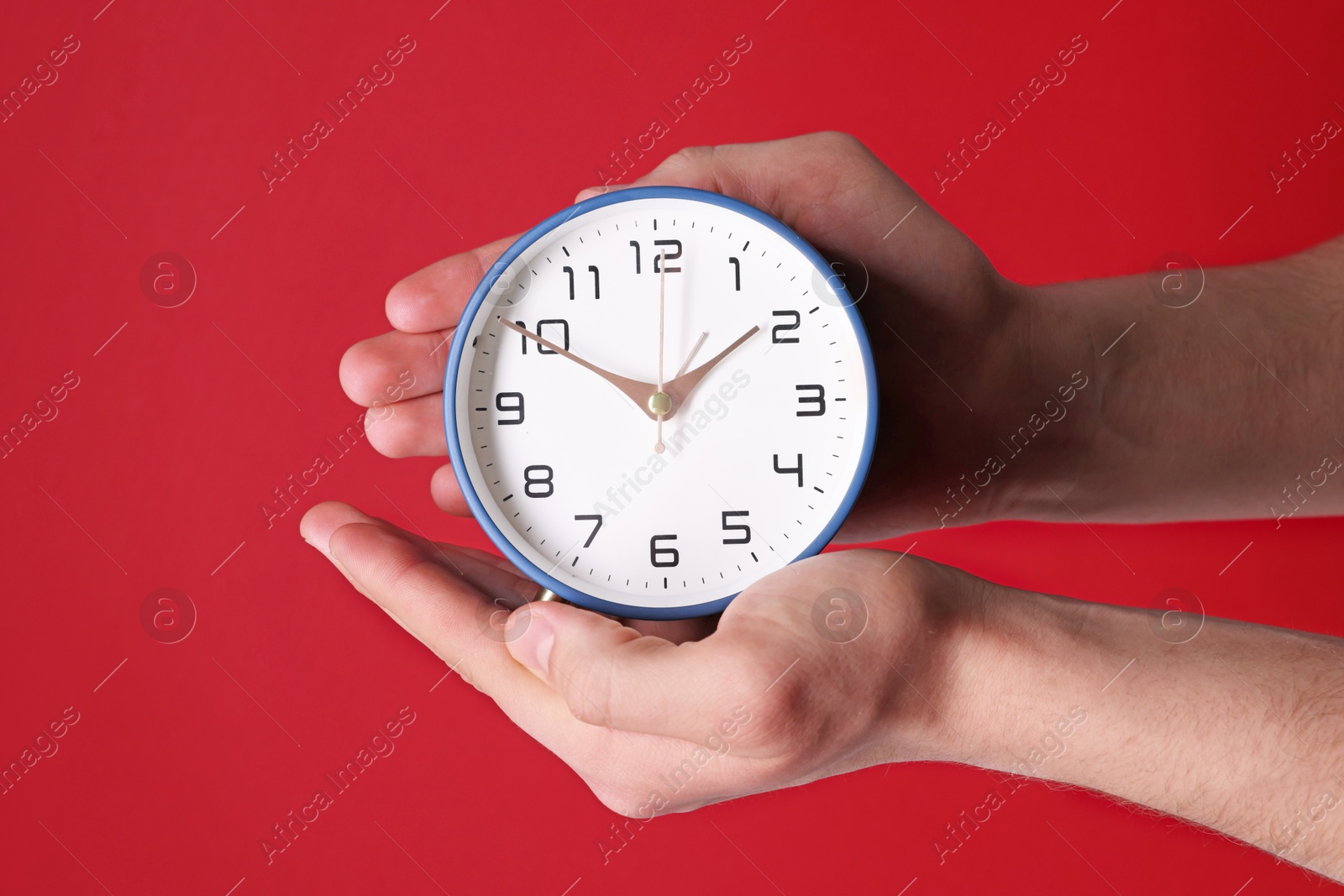 Photo of Man with alarm clock on red background, closeup