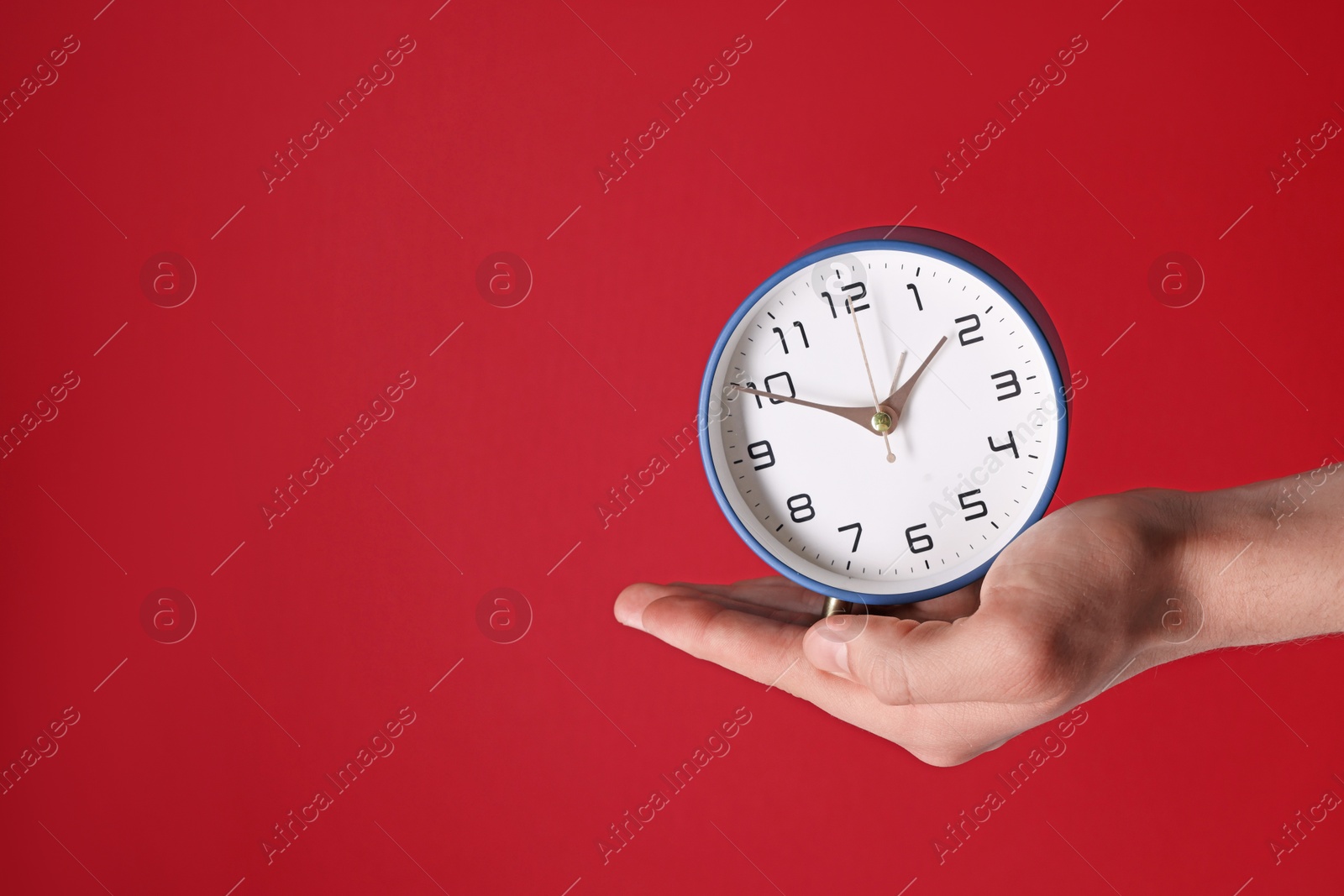 Photo of Man with alarm clock on red background, closeup. Space for text