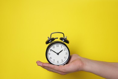 Photo of Man with alarm clock on yellow background, closeup. Space for text