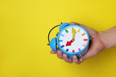 Man with alarm clock on yellow background, closeup. Space for text