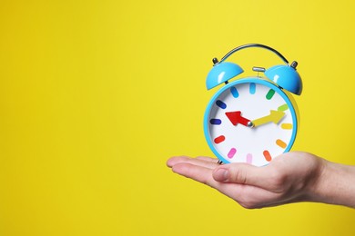 Photo of Man with alarm clock on yellow background, closeup. Space for text