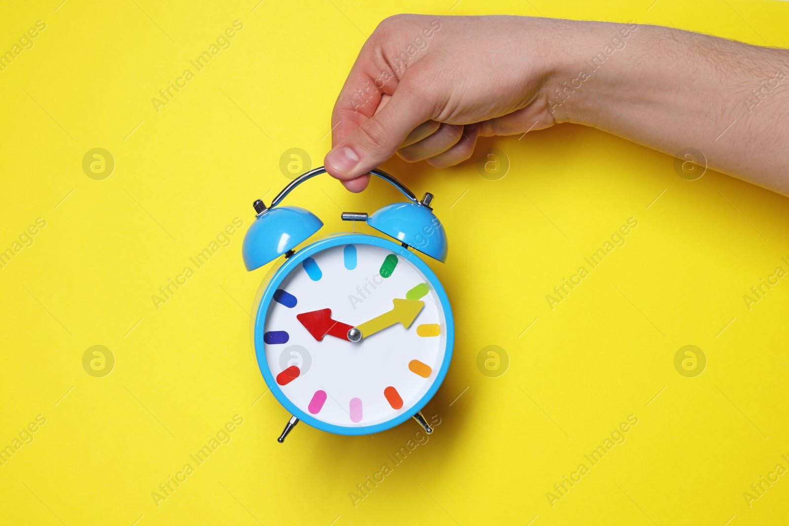 Photo of Man with alarm clock on yellow background, closeup. Space for text