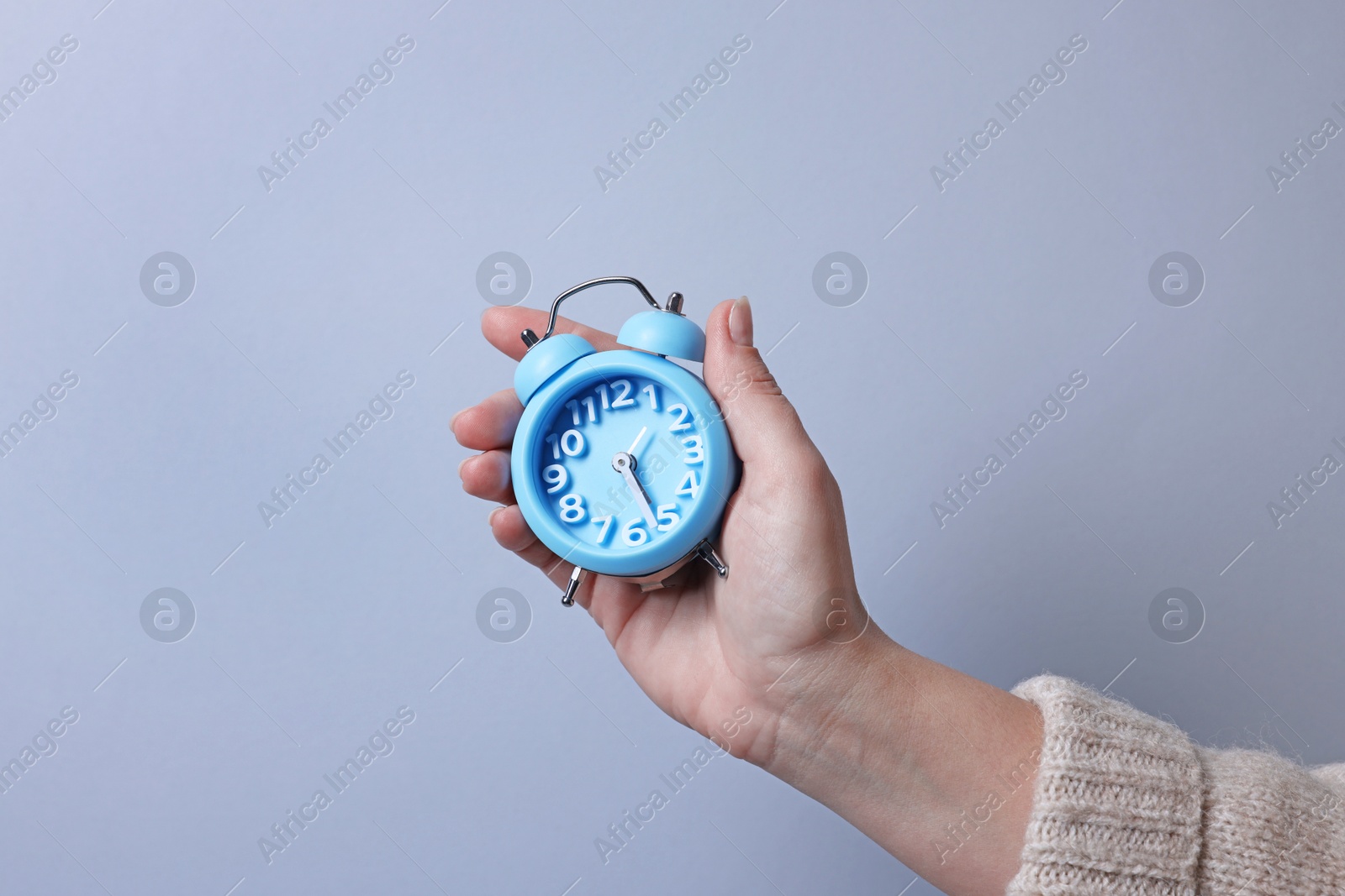 Photo of Woman with alarm clock on grey background, closeup