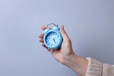 Photo of Woman with alarm clock on grey background, closeup