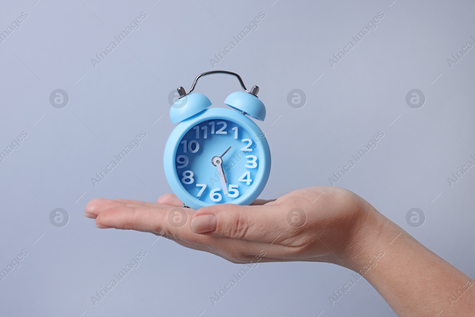 Photo of Woman with alarm clock on grey background, closeup