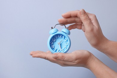 Photo of Woman with alarm clock on grey background, closeup