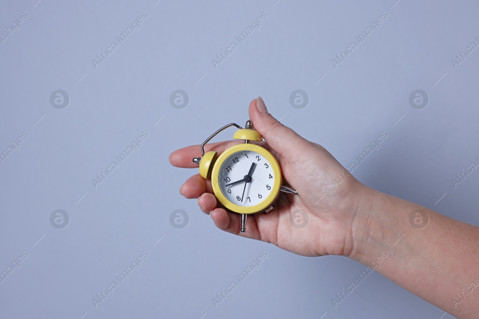 Photo of Woman with alarm clock on grey background, closeup. Space for text