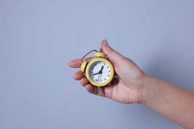 Woman with alarm clock on grey background, closeup. Space for text