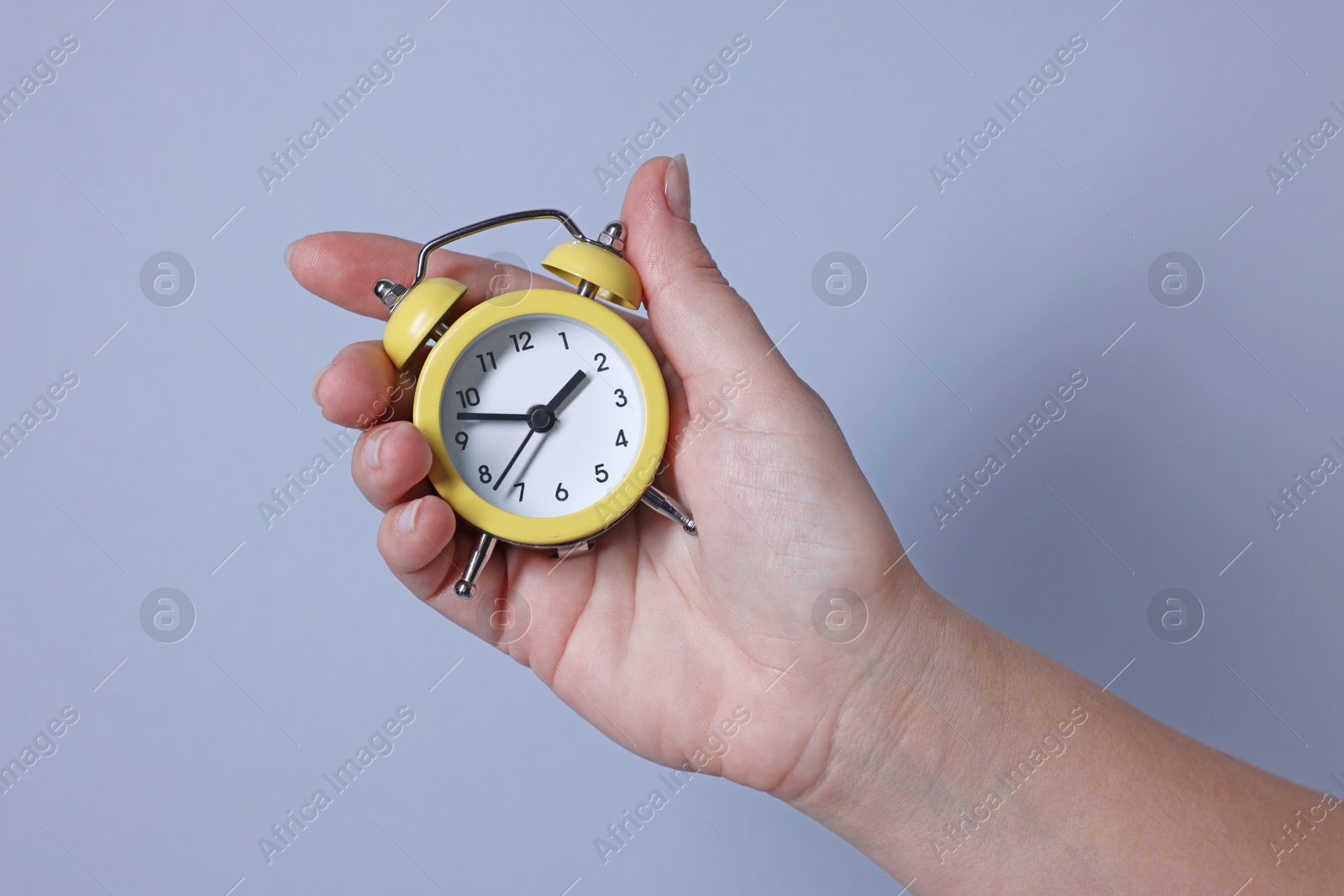 Photo of Woman with alarm clock on grey background, closeup