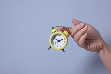 Photo of Woman with alarm clock on grey background, closeup. Space for text