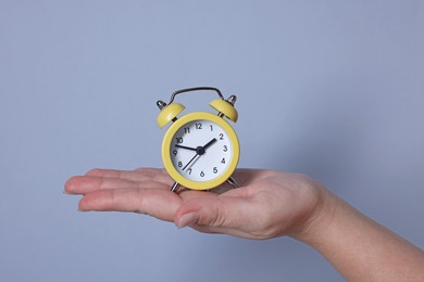 Photo of Woman with alarm clock on grey background, closeup