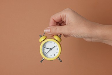 Photo of Woman with alarm clock on brown background, closeup